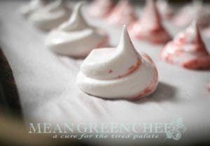 Strawberry Meringue Cookies with swirls of strawberry purée piped onto a baking sheet lined with parchment paper.