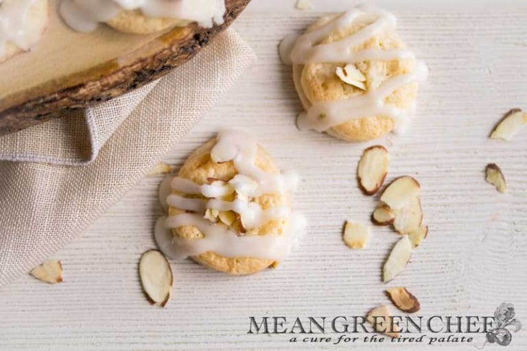 Overhead photo of Almond Pastry Cookies on white wooden background with roasted almonds sprinkled around.