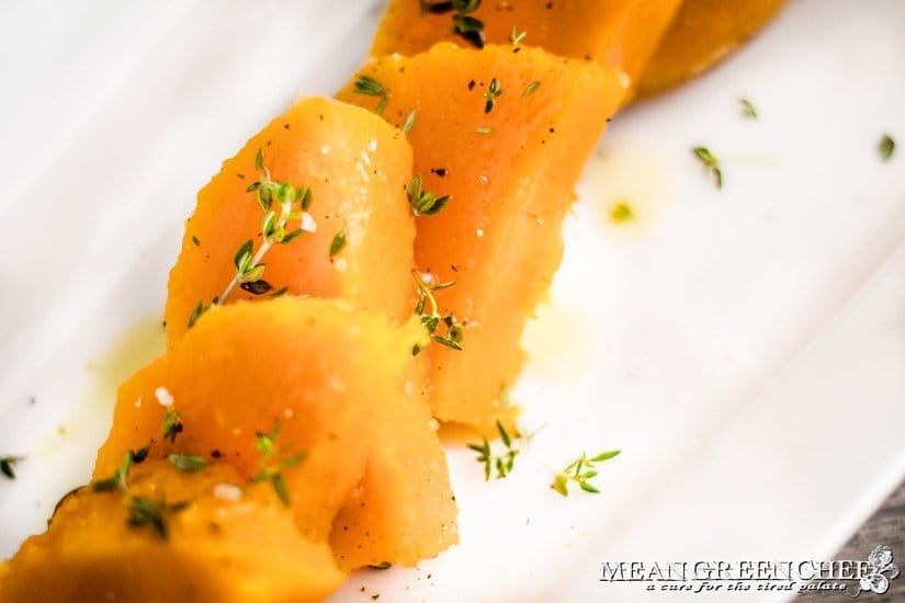 Butternut Squash on a white platter garnished with fresh thyme.