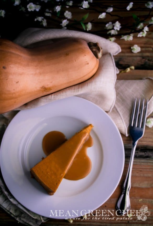 Pumpkin Spice Cheesecake with Caramel Sauce Recipe on a white plate sitting on a rustic wooden background.