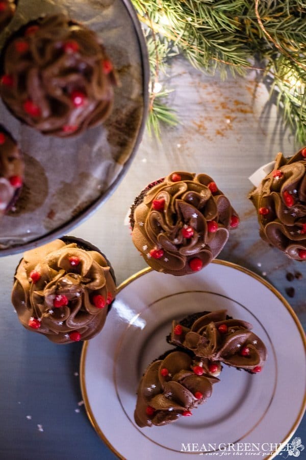 Overhead photo of Bakery Style Chocolate Cupcakes with high swirls of chocolate frosting that have been decorated with red frosting berries and a sprinkle of silver stars.