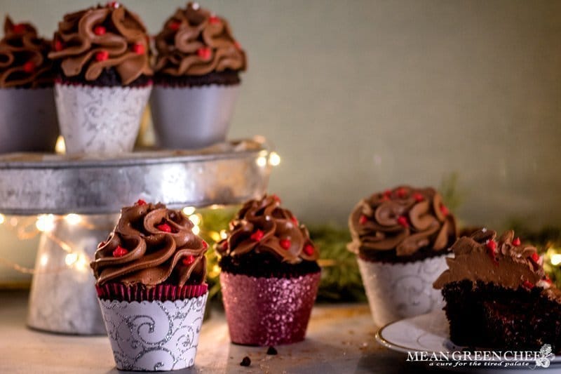 Side photo of Bakery Style Chocolate Cupcakes decorated with a high swirl of chocolate frosting red frosting berries and a sprinkle of silver stars in a scalloped gray, silver, and pink cupcake wrappers.