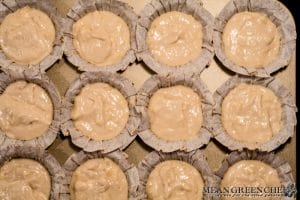 Cupcake liners sitting in a muffin tin filled with Pink Champagne Cupcake batter.