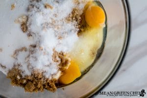 Ingredients for Best Ever Molasses Cookies brown and white sugar with eggs in a large glass bowl