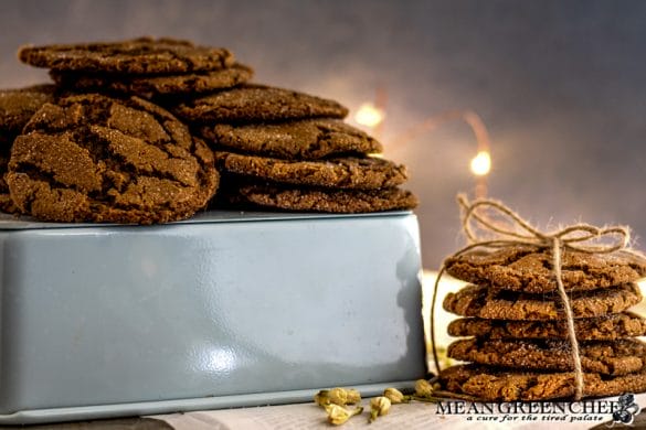 Stack of Molasses Cookies, tied with twine and sitting on newspaper that has been scattered with white flower buds.