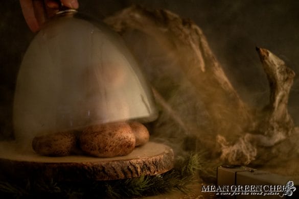 Portobello mushrooms smoking with bourbon wood under a glass dome.