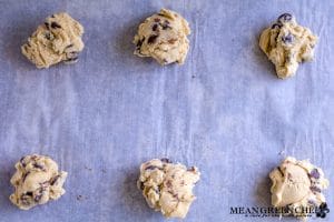 Bakery Style Chocolate Chip Cookie dough ready to be baked, sitting on a sheet pan lined with parchment paper.