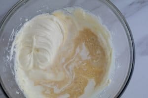 Cream cheese frosting ingredients being whipped in a glass bowl.