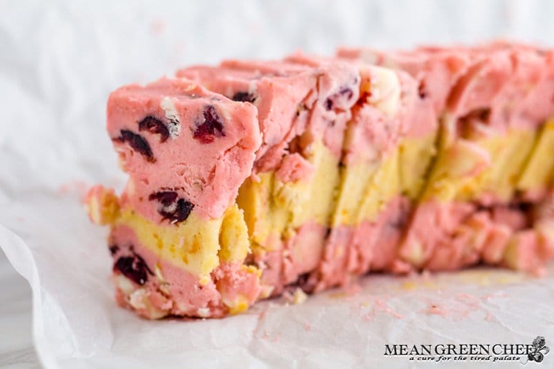 Photo of layered Orange Cranberry Icebox Cookie dough sliced on parchment paper.