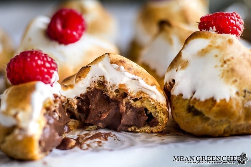Rich Chocolate Creme Patissiere Pastry Cream in cream puffs with Swiss Meringue and red raspberries on top.