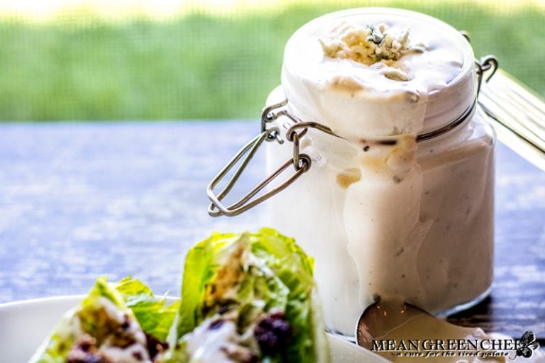 Buttermilk Blue Cheese Dressing in a glass jar with a wedge salad in the forefront.