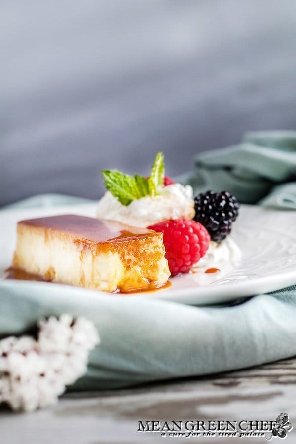Classic Flan plated with berries and whipped cream.