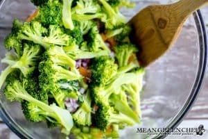 Broccoli being tossed into chicken salad.