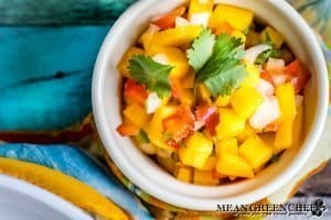 Fresh mango salsa in a bowl on a old blue wooden background.