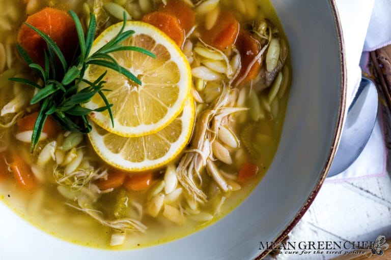 Lemon Chicken Orzo Soup in a light blue bowl, garnished with lemons.