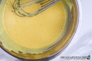 Honey Mustard Dipping Sauce whisked together in a metal bowl that is situated on a white marble countertop.